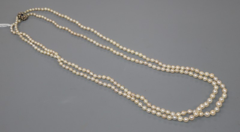 A double strand graduated cultured pearl necklace, with sapphire and diamond set white metal clasp, 70cm.